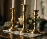 Three brass candlesticks on a table.